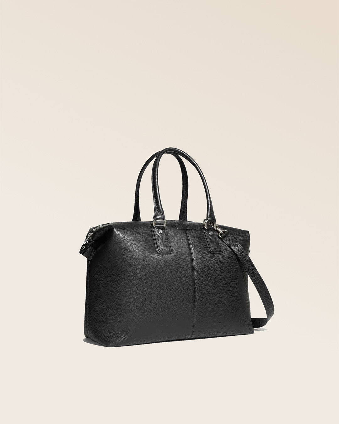 Notre sac de voyage Escapade petit modèle en cuir façon vigogne noir vu de quart en studio.
