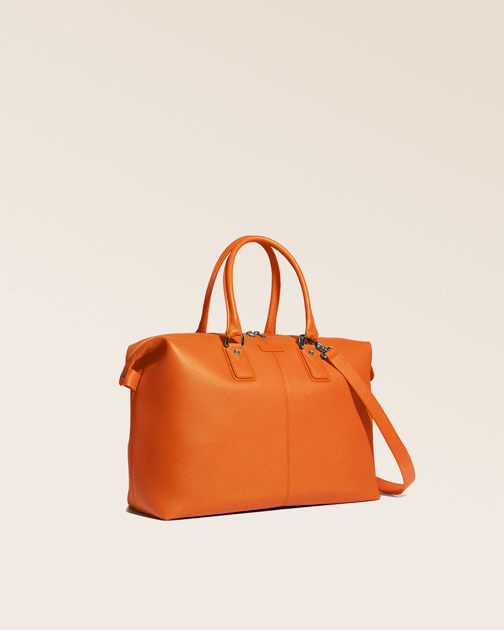Notre sac de voyage Escapade petit modèle en cuir façon vigogne orange vu de quart en studio.