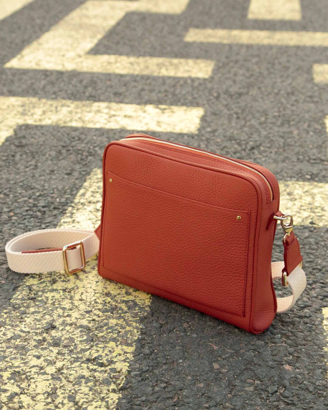 Notre sac Zoom en cuir façon vigogne terracotta et bandoulière sangle coton vu de quart en ambiance.