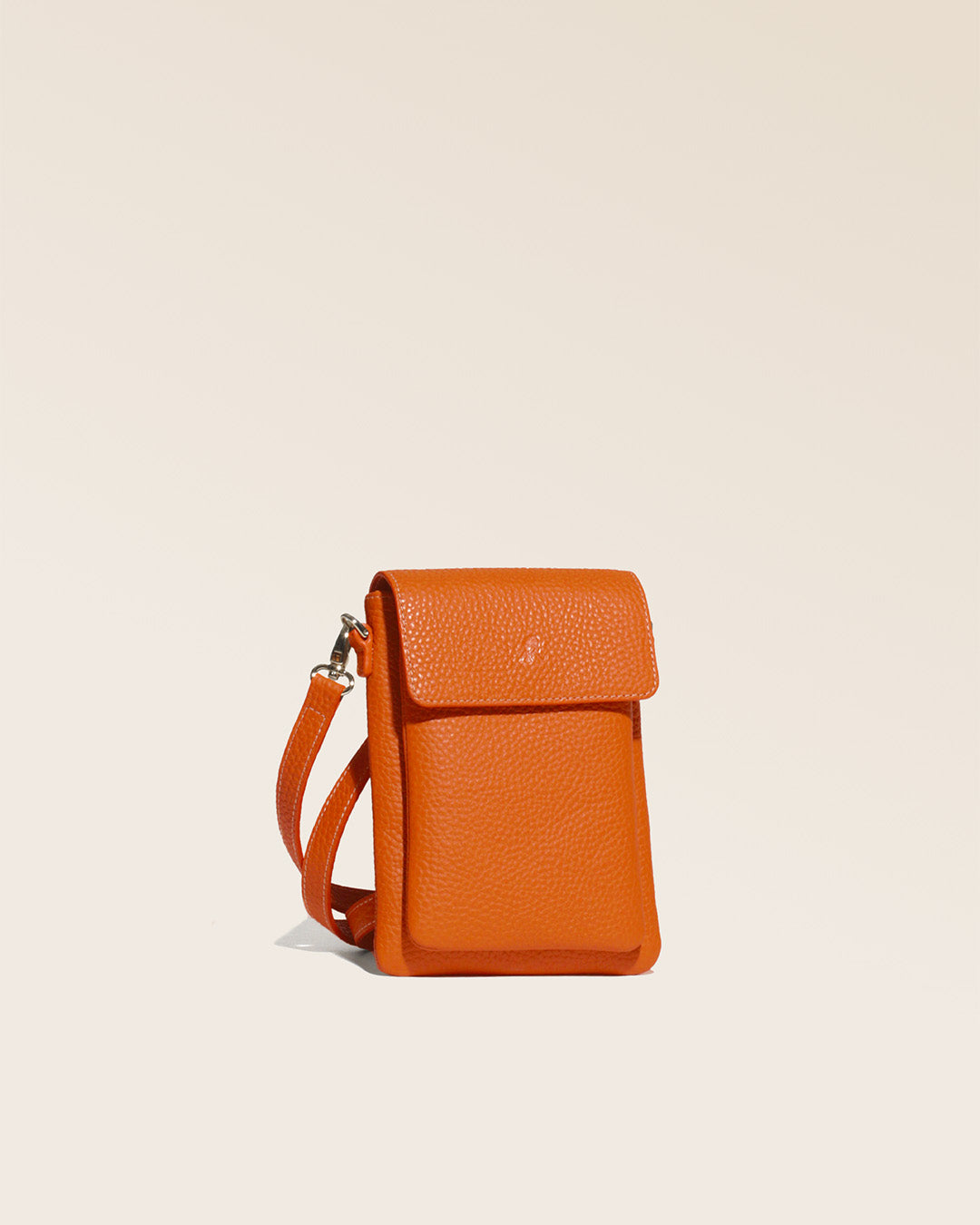 Our seagull clutch bag in orange vicuña-style leather, seen from the quarter in the studio.