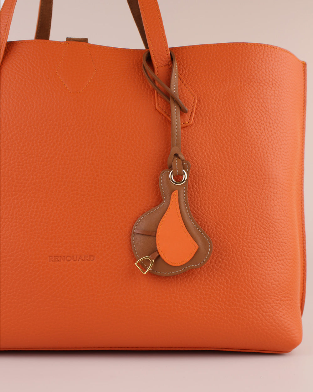 Le bijou de sac Selle Renouard en cuir lisse orange et cuir lisse camel, vu sur notre Cabas Shopper en cuir vigogne orange.