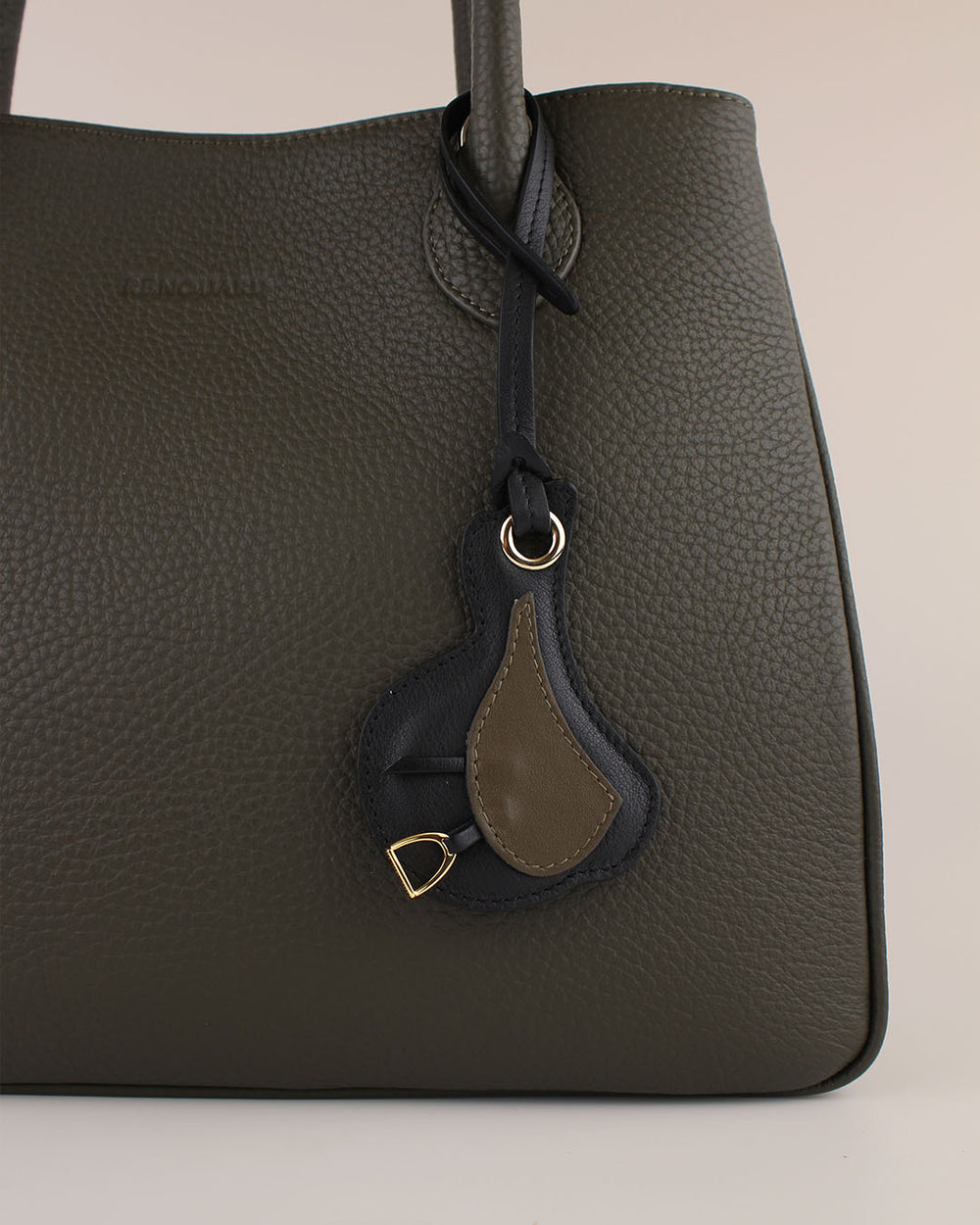 Le bijou de sac Selle Renouard en cuir lisse truffe et cuir lisse noir, vu sur notre sac ker Balmoral en cuir vioggne kaki.
