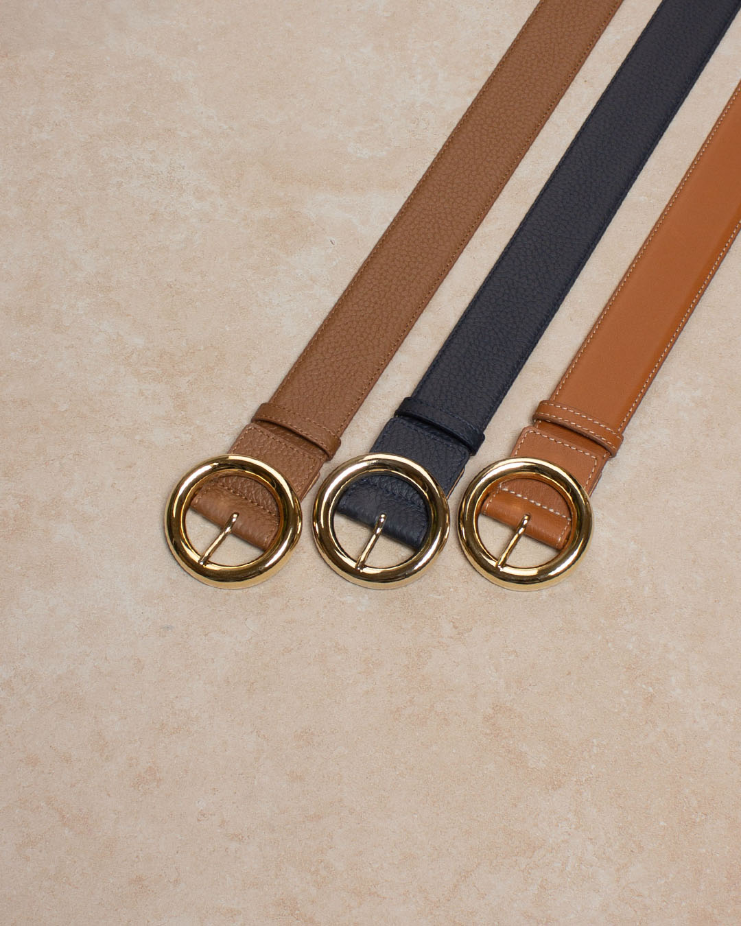 Notre ceinture Tamara Renouard en cuir façon vigogne marine, fauve, et vintage camel avec une boucle dorée vue en ambiance.