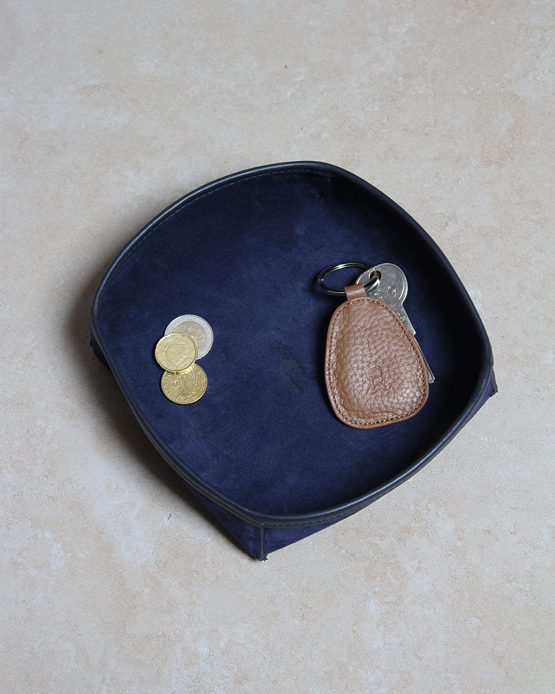 Notre porte-clé Anneau Renouard en cuir vigogne fauve, vu en ambiance dans notre vide-poche kiwi en cuir veau velours encre.