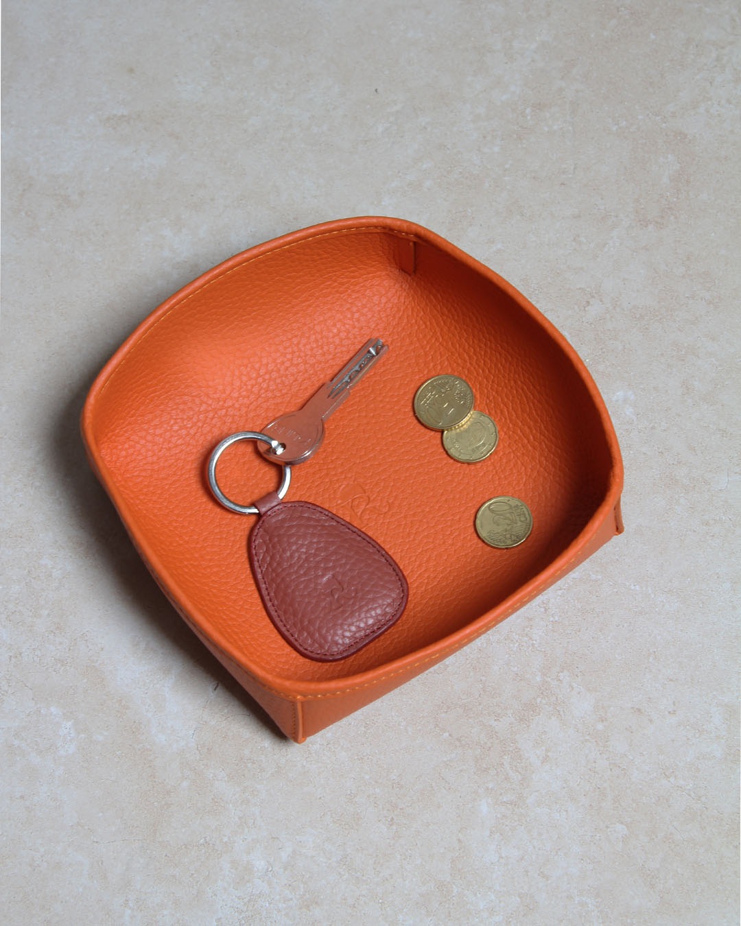 Notre porte-clé Anneau Renouard en cuir vigogne terracotta, vu en ambiance dans notre vide-poche kiwi en cuir vigogne orange.
