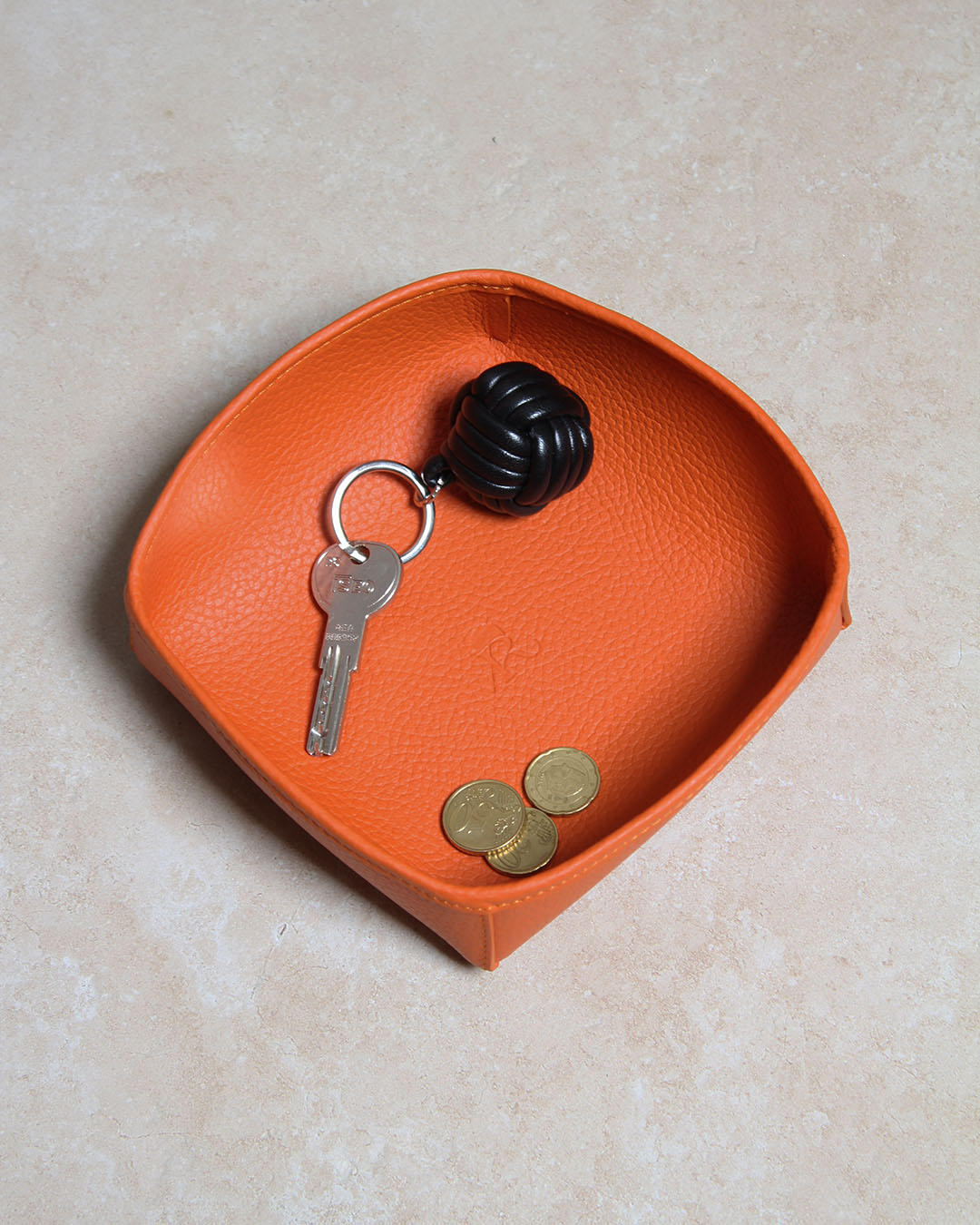 Notre porte-clés Moussaillon en cuir noir, vu en ambiance dans notre vide-poche kiwi en cuir vigogne orange.
