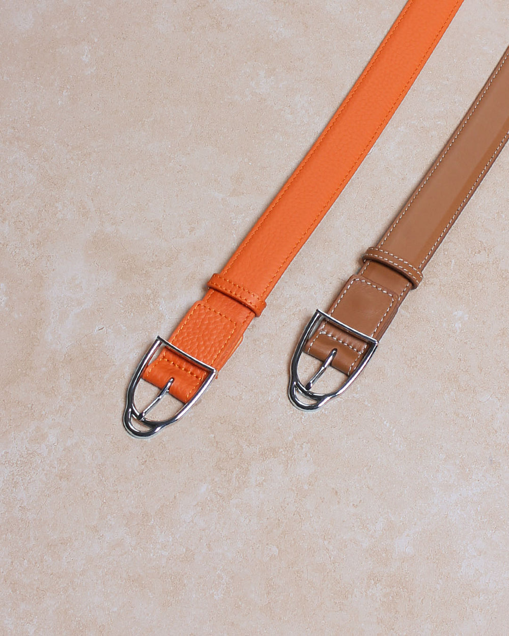 Nos ceintures Jockey Renouard en cuir façon vintage camel et vigogne orange, vue d'ambiance en studio.