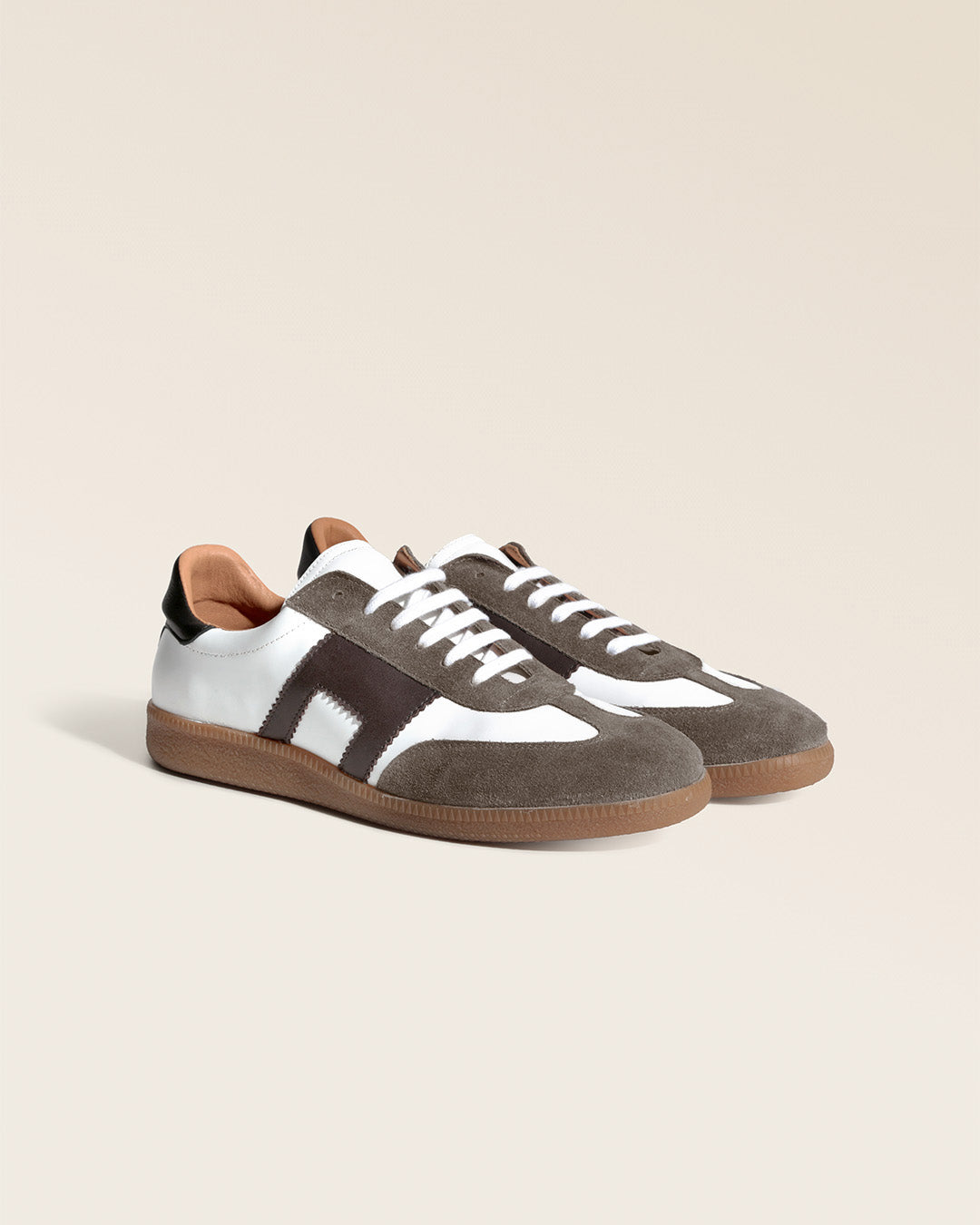 Nos sneakers Lucas Renouard pour homme en cuir lisse craie et chocolat surmontées d'un velours taupe, vues de quart en studio.