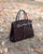 Le sac Prestige PM Renouard en cuir veau velours espresso et lisse ébène, vu de quart en ambiance.