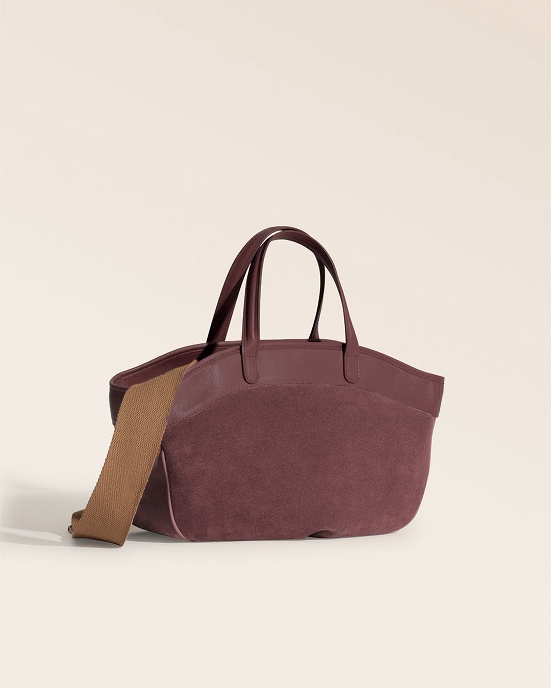 Le sac Sarah Renouard en cuir veau velours acajou et lisse acajou, avec sa bandoulière coton camel, vu de quart en studio.