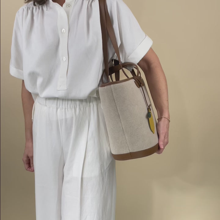 Notre sac panier Corfou Renouard en toile de lin et cuir façon vigogne fauve, vu porté en studio.