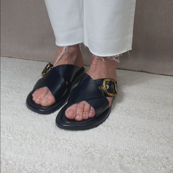 Nos mules Anaïs Renouard en cuir lisse bleu marine, vues portées par un mannequin en studio.