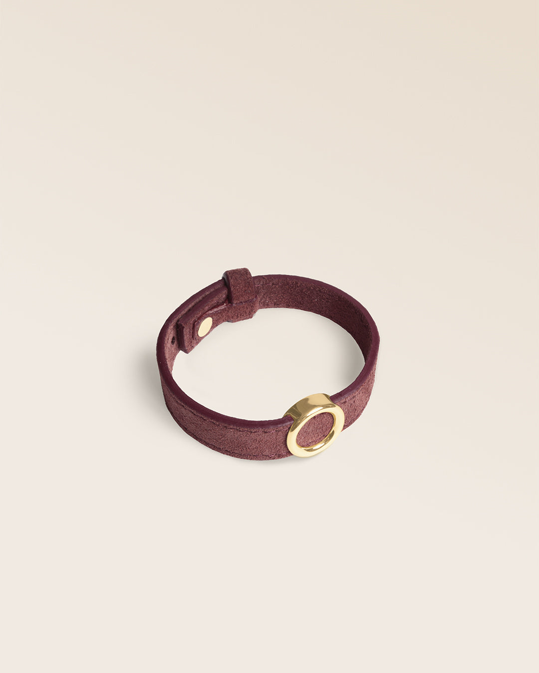 Le bracelet Capsule Renouard en cuir veau velours acajou et cuir lisse acajou, avec son accessoire doré, vu de quart en studio.