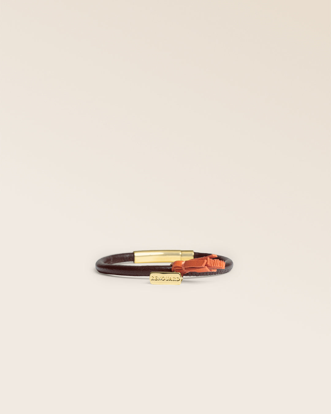 Le bracelet Jumping Renouard en cuir d'agneau lisse chocolat et son pompon orange, vu de face en studio.