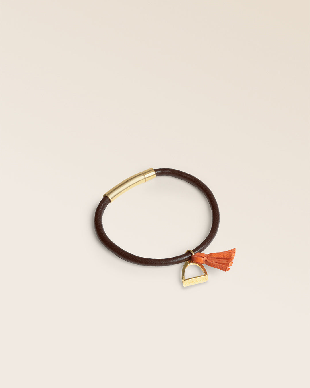 Le bracelet Jumping Renouard en cuir d'agneau lisse chocolat et son pompon orange, vu de quart en studio.