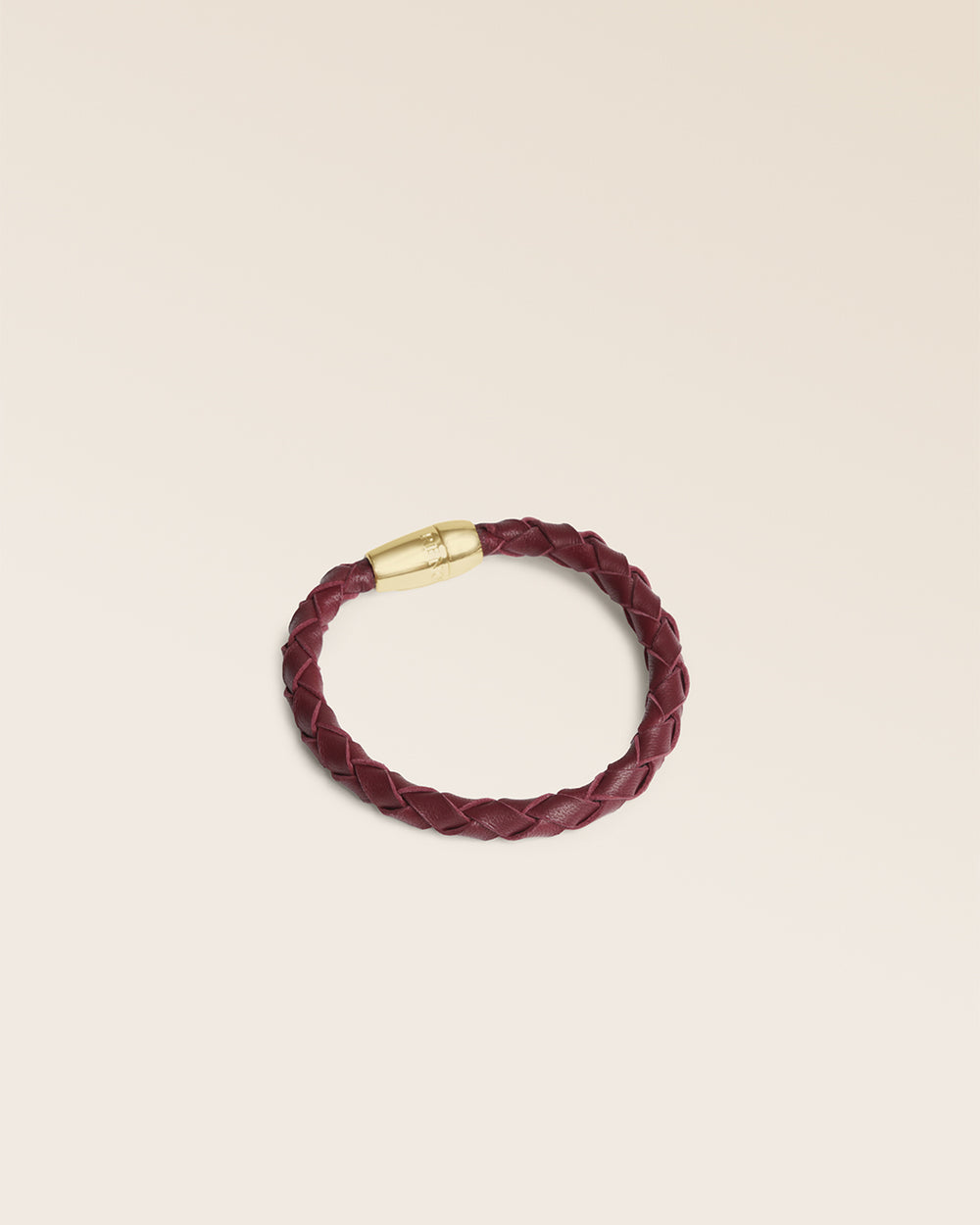 Le bracelet Mohican Renouard en cuir tressé bordeaux et son fermoir doré, vu de quart en studio.