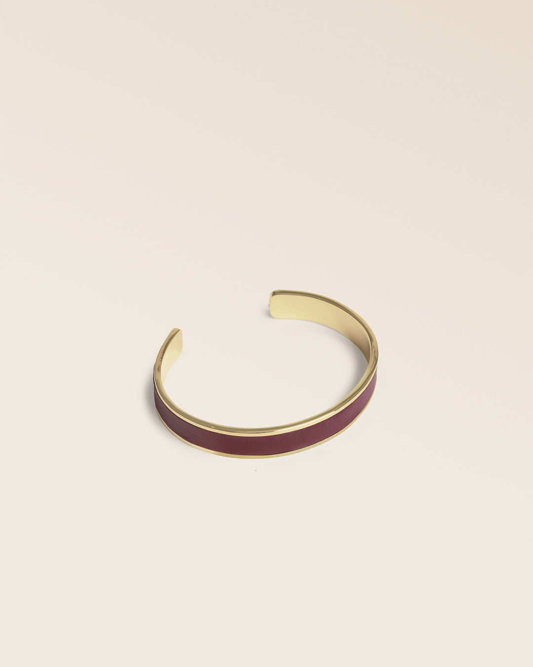 Le bracelet Pacôme Renouard doré et cuir lisse acajou, vu de quart en studio.