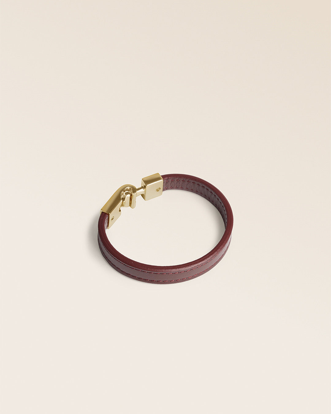 Le bracelet Roméo Renouard en cuir lisse acajou et son fermoir bijou doré pâle, vu de quart en studio.