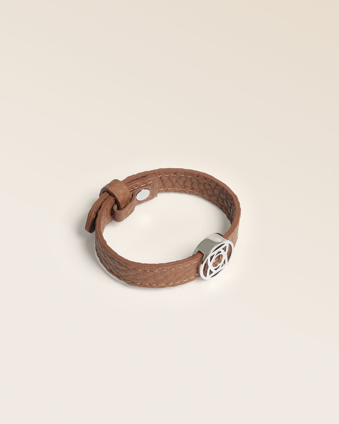 Le bracelet Alezan Renouard en cuir façon vigogne fauve et accessoire nickelé, vu de quart en studio.