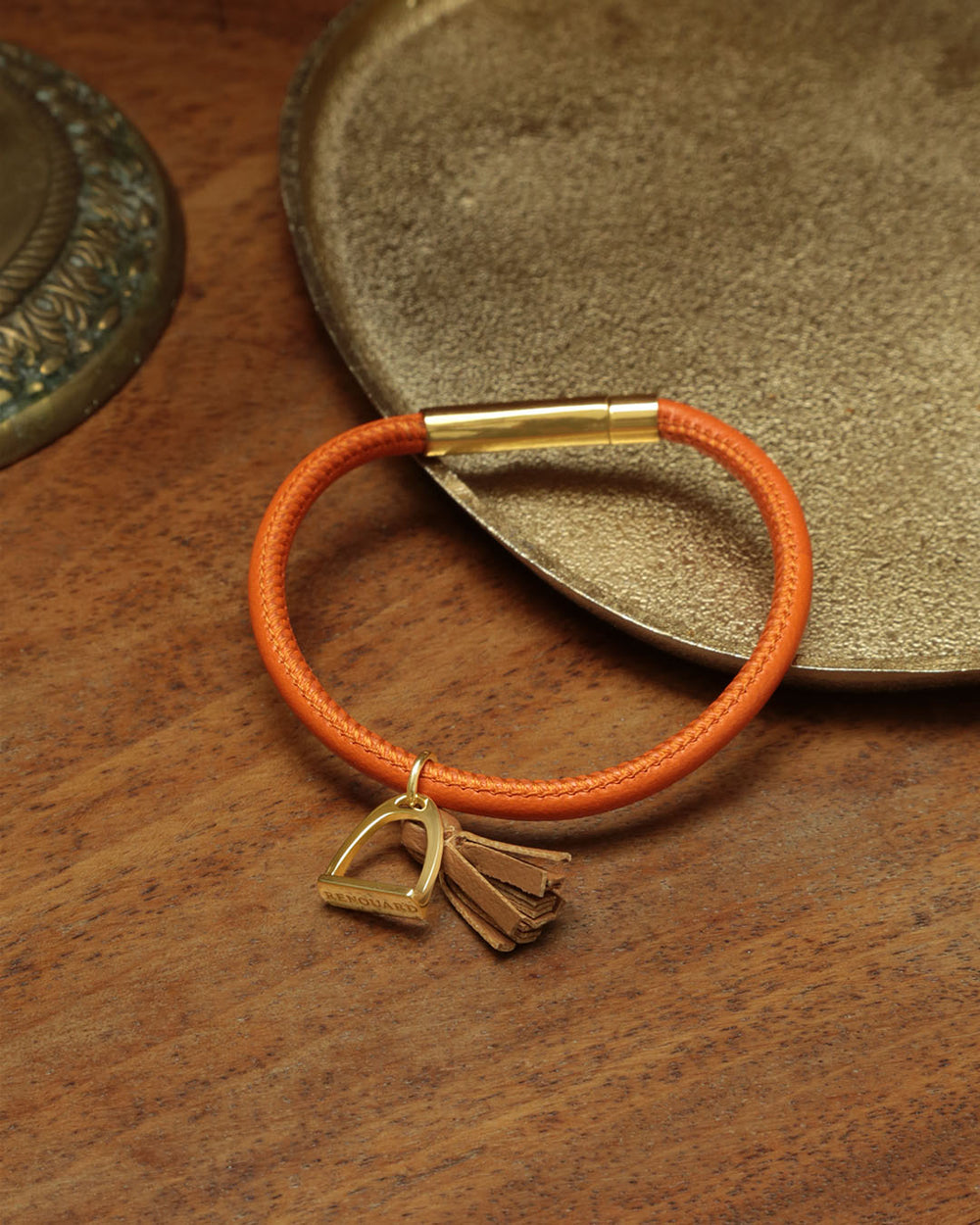 Notre bracelet Jumping Renouard en cuir d'agneau orange et pompon camel, vu en ambiance.