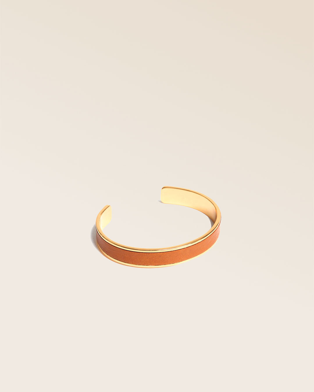 Notre bracelet Pacôme doré en cuir lisse camel vu de quart en studio.