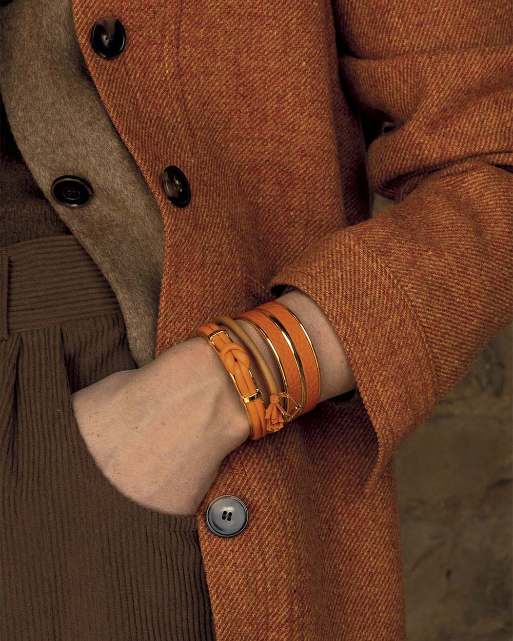 Nos bracelets Doris, Jumping et Adeline Renouard en cuir camel et orange, vus portés par notre mannequin. 