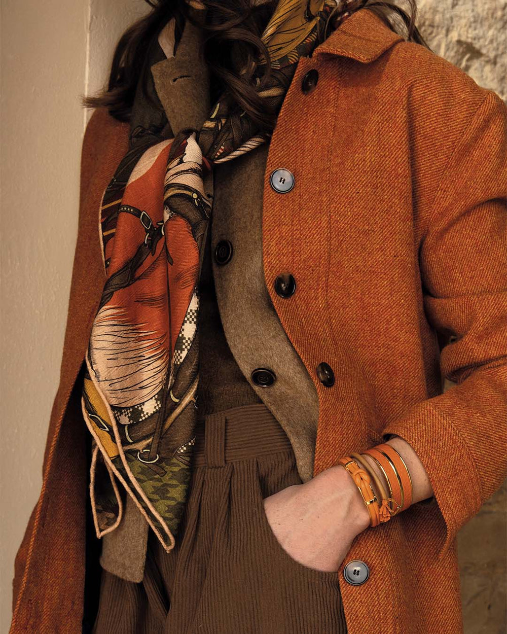Notre châle Percherons Renouard en laine et soie roulotté main, dans sa verison kaki, orange et terracotta, vu porté par notre mannequin. 