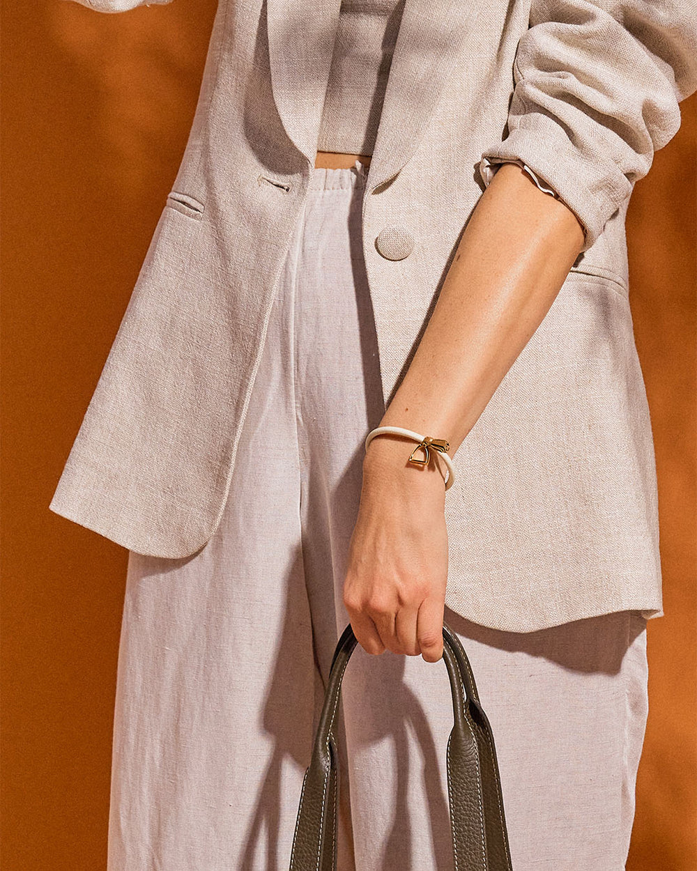 Notre bracelet Jumping Renouard en cuir d'agneau craie et pompon camel, vu porté par notre mannequin.