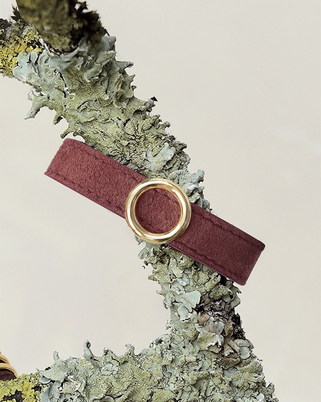 Le bracelet Capsule Renouard en cuir veau velours acajou et cuir lisse acajou, avec son accessoire doré, vu de face en ambiance.