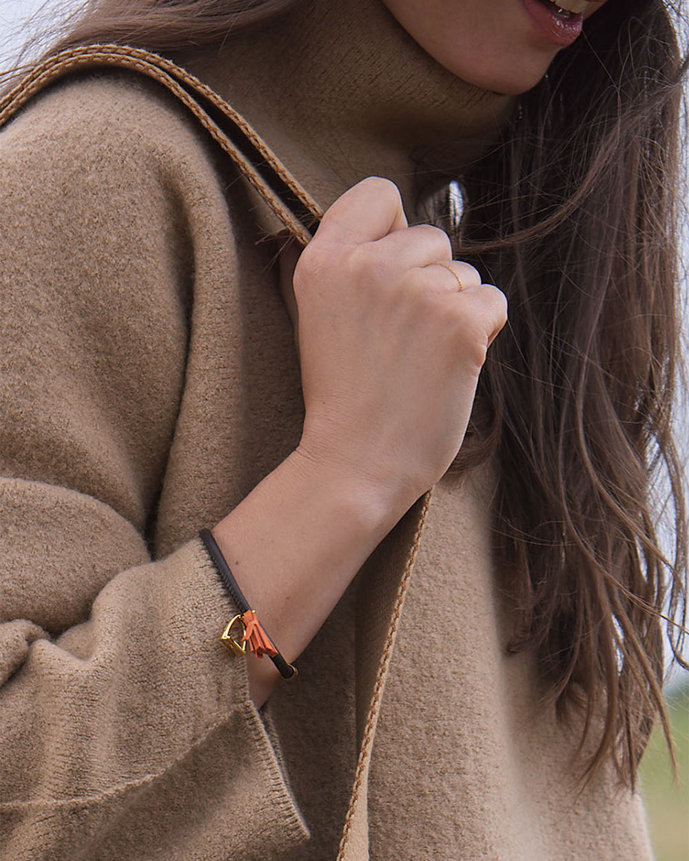 Le bracelet Jumping Renouard en cuir d'agneau lisse chocolat et son pompon orange, vu porté par notre mannequin. 