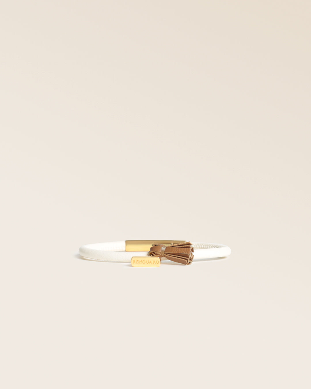 Notre bracelet Jumping Renouard en cuir d'agneau craie et pompon camel, vu de face en studio.