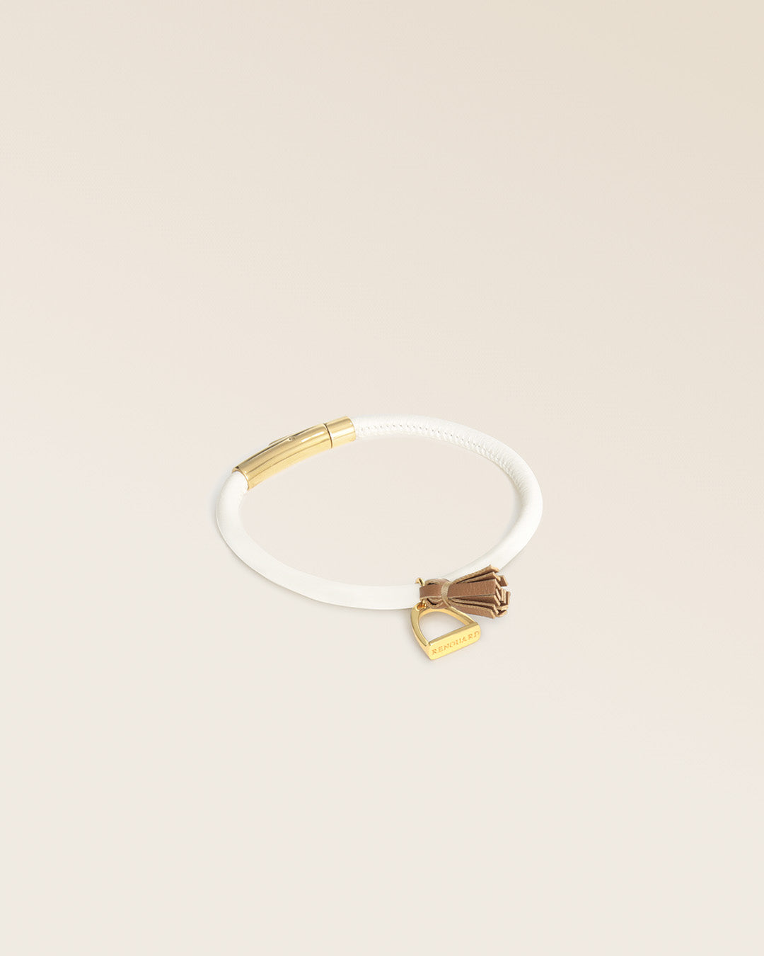 Notre bracelet Jumping Renouard en cuir d'agneau craie et pompon camel, vu de quart en studio.