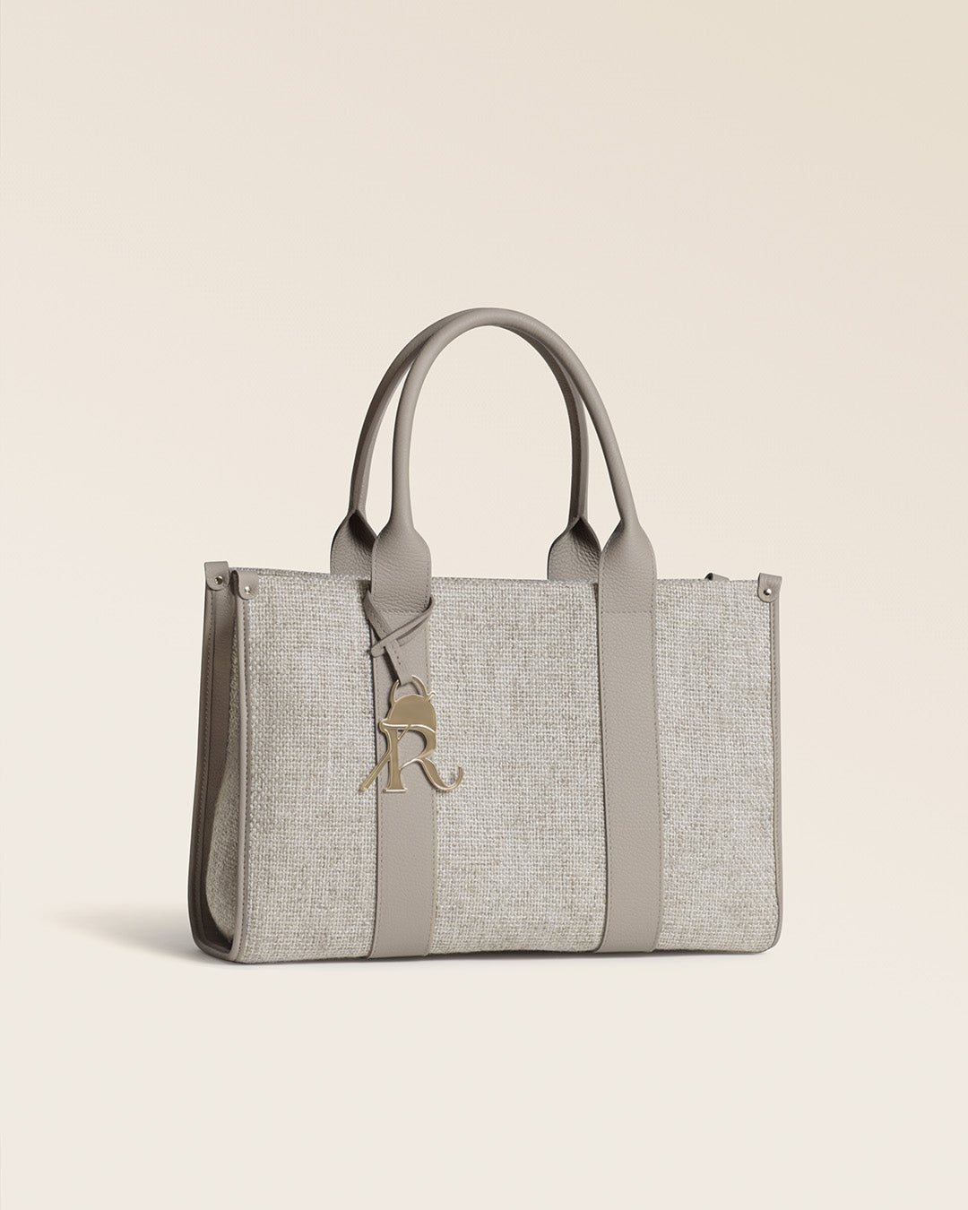 Notre sac cabas Nina Renouard en toile minérale et en cuir façon vigogne corde, vu de quart en studio.