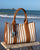 Notre cabas Nina Renouard en toile transat et cuir vintage camel, vu de face en ambiance.
