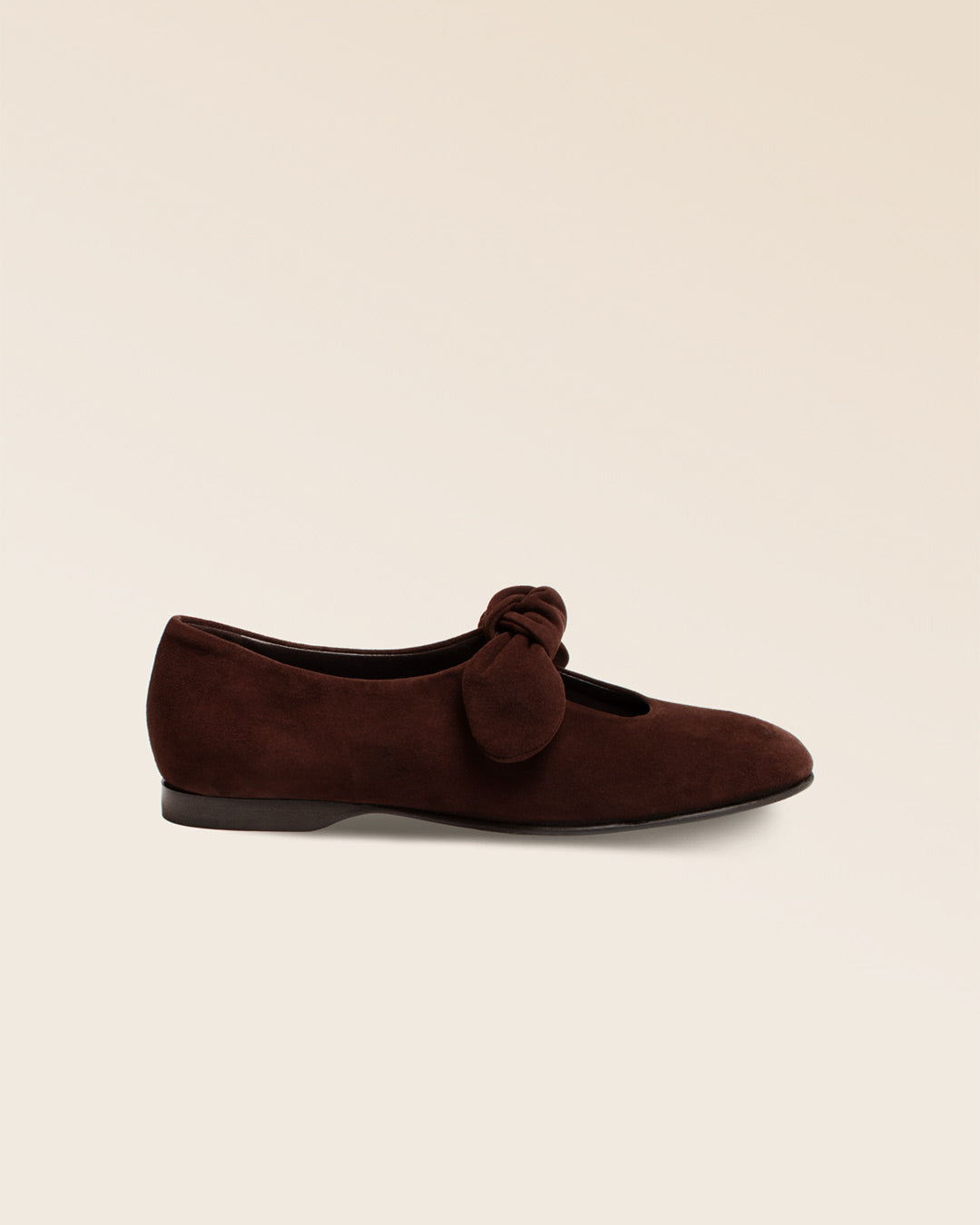 Nos babies Céleste Renouard en cuir nubuck chocolat et leur joli noeud sur le pied, vues de côté en studio.