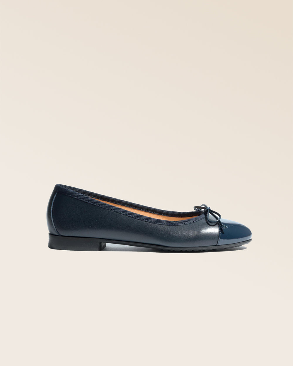 Nos ballerines Friandise Renouard en cuir lisse bleu marine et bout vernis, vues de côté en studio.