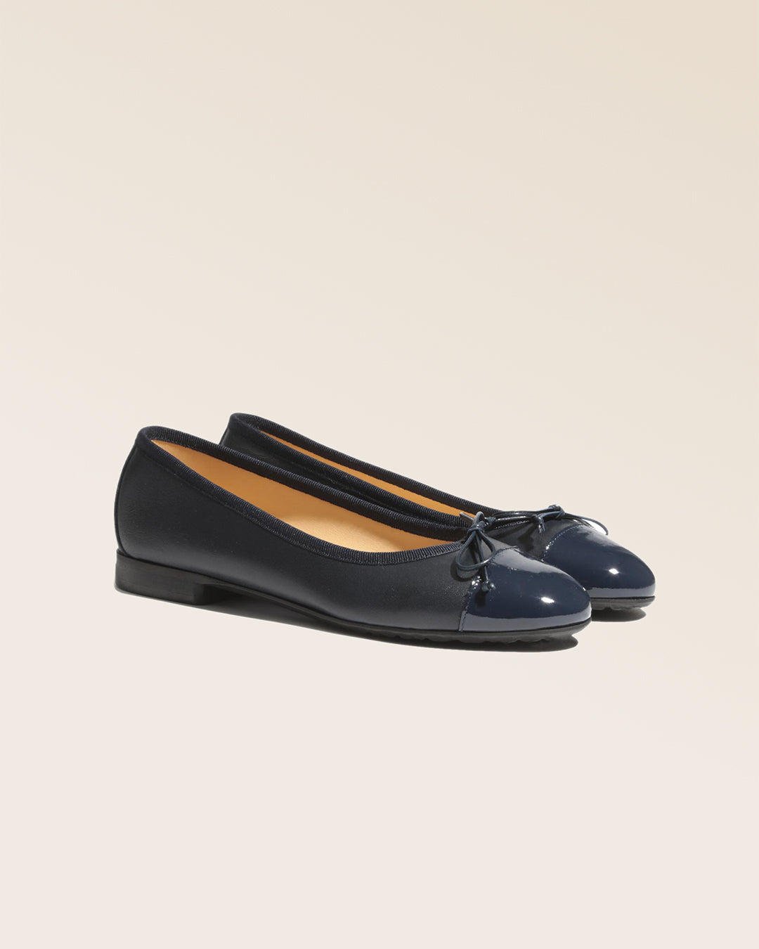 Nos ballerines Friandise Renouard en cuir lisse bleu marine et bout vernis, vues de quart en studio.