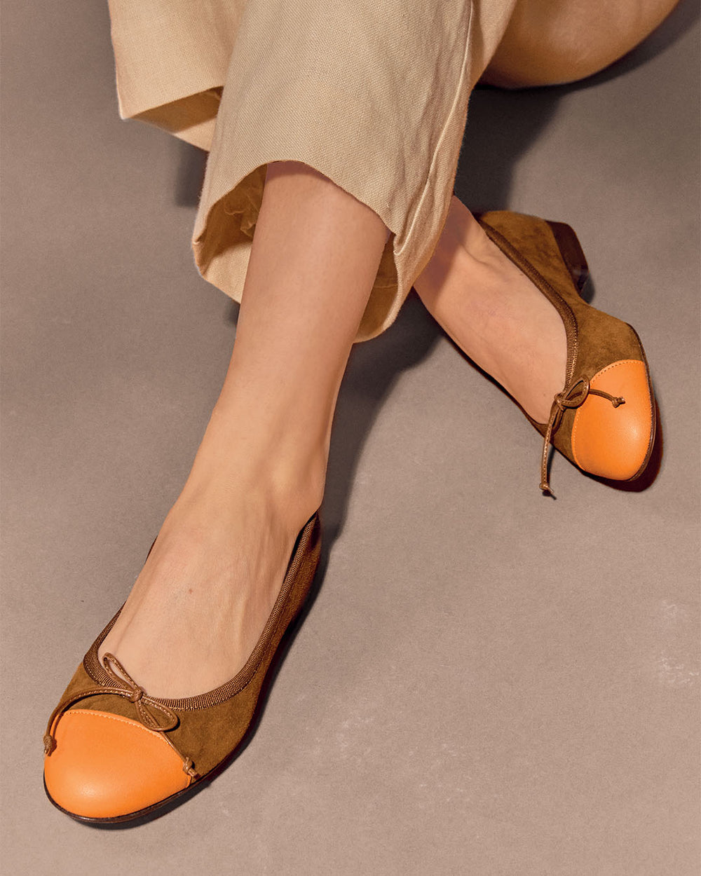 Nos ballerines Friandise Renouard en cuir nubuck noisette et lisse orange, vues portées par un mannequin.