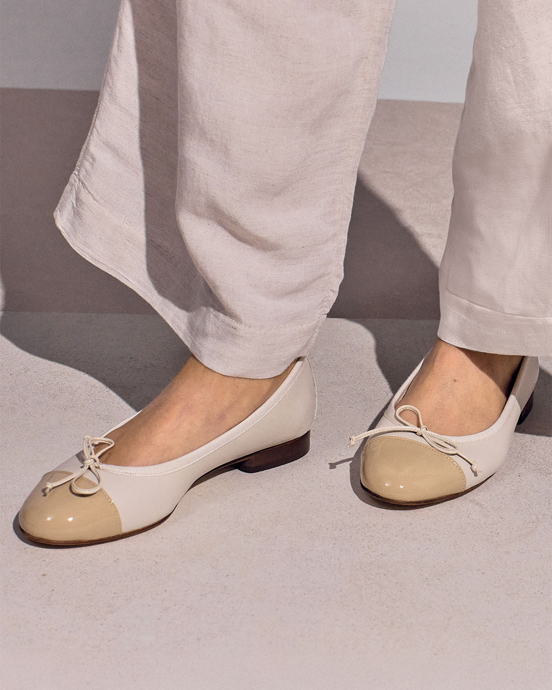 Nos ballerines Friandise Renouard en cuir lisse crème et cuir vernis beige, vues portées par un mannequin.