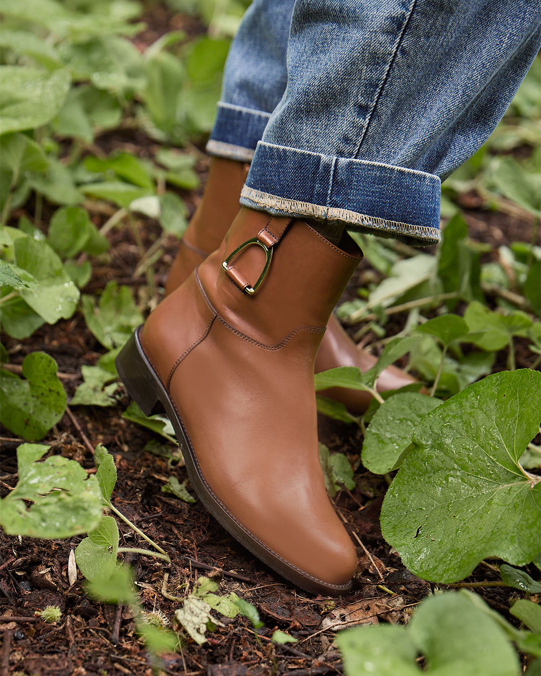 Les boots Paddock Renouard en cuir de veau lisse gold et leur accessoire étrier doré pâle, vues portées par notre mannequin.