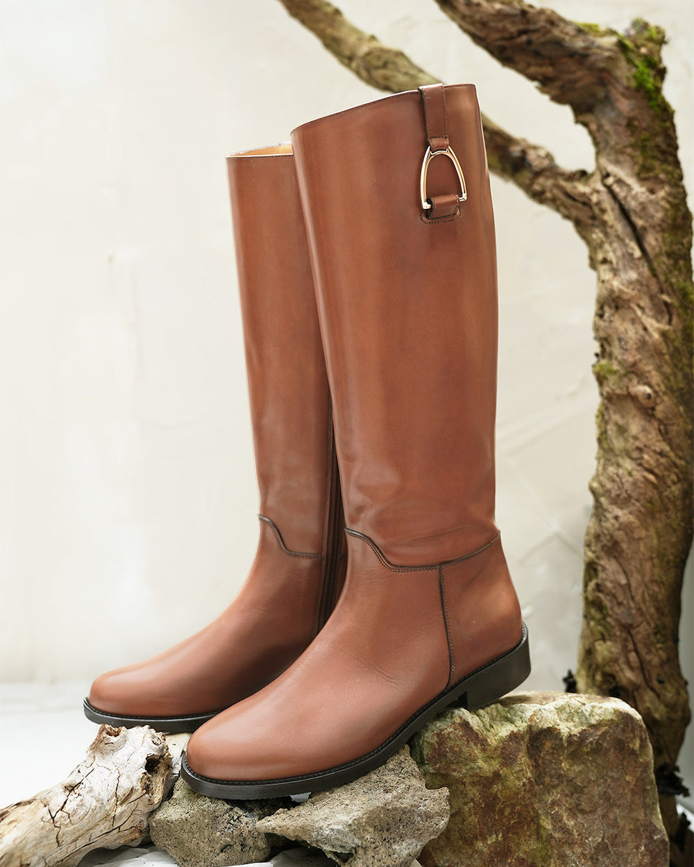 Les bottes Horse Renouard en cuir de veau lisse gold et leur accessoire étrier doré pâle, vues de quart en ambiance.