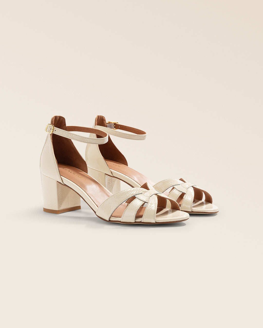 Nos nu-pieds Baba Renouard en cuir vernis crème, vus de quart en studio.