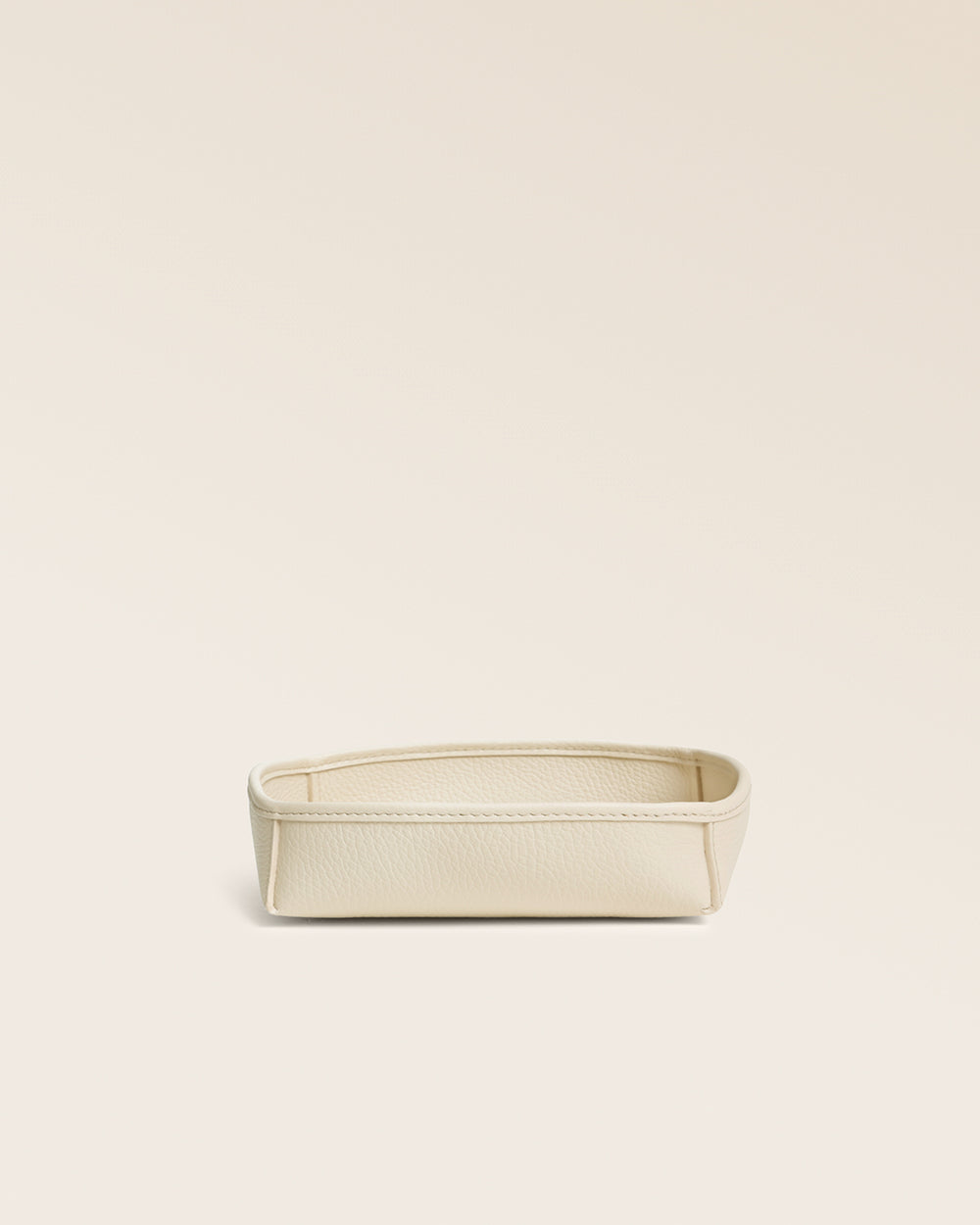 Notre vide-poches Kiwi Renouard en cuir façon vigogne crème, vu de face en studio.