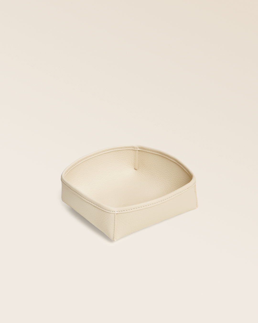 Notre vide-poches Kiwi Renouard en cuir façon vigogne crème, vu de quart en studio.