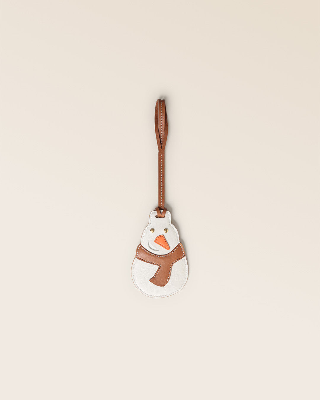 Notre bijou de sac Bonhomme de Neige Renouard, en cuir vintage camel et craie, vu de face en studio.