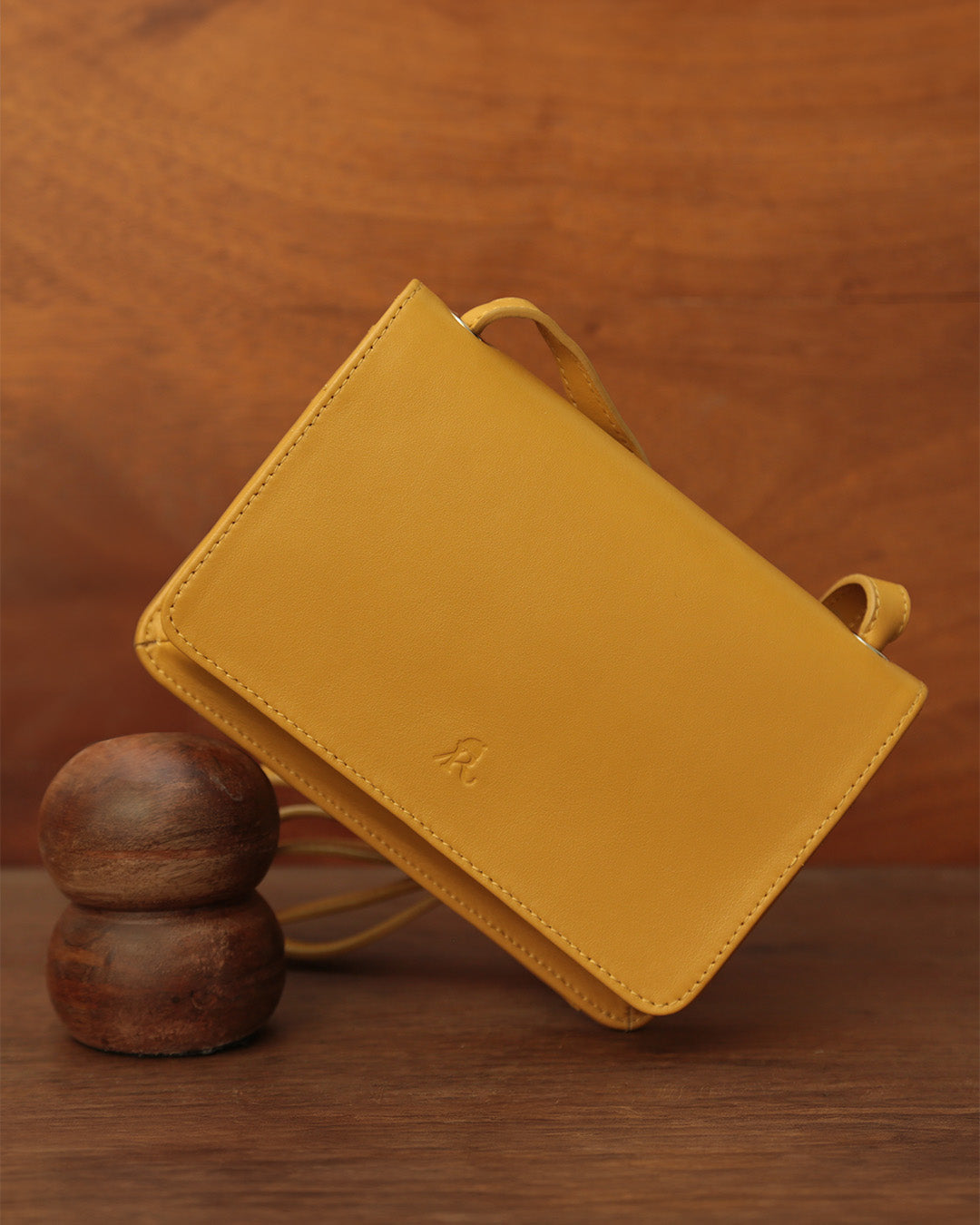 Notre pochette Fréhel Renouard en cuir lisse curry, vue de face en ambiance.