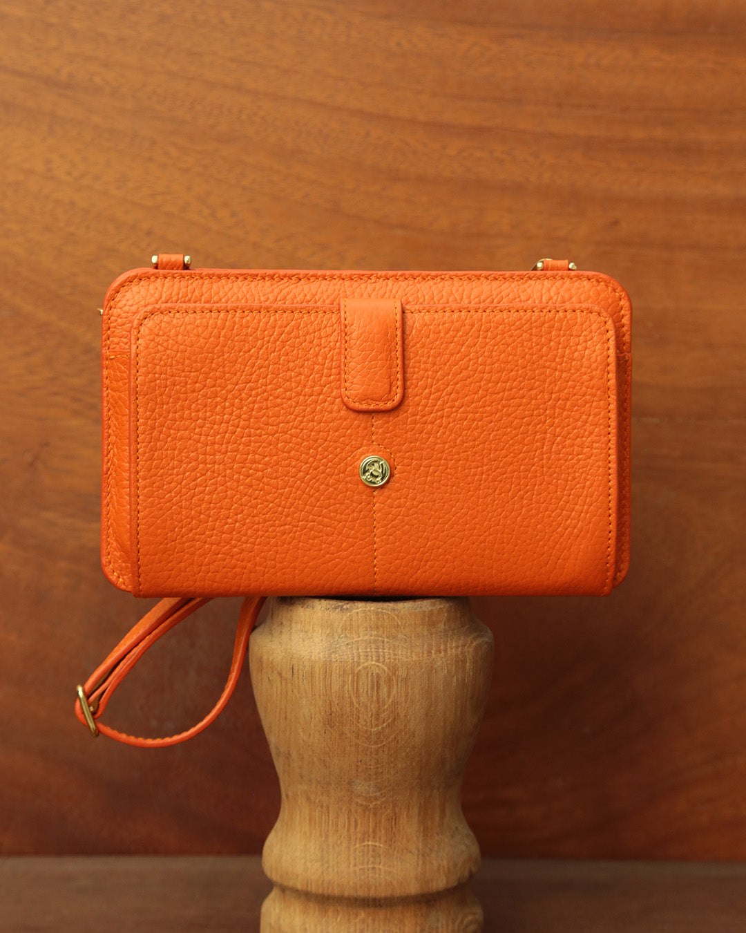 Notre pochette Manolo Renouard en cuir façon vigogne orange, vue de face en ambiance.