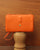Notre pochette Manolo Renouard en cuir façon vigogne orange, vue de face en ambiance.