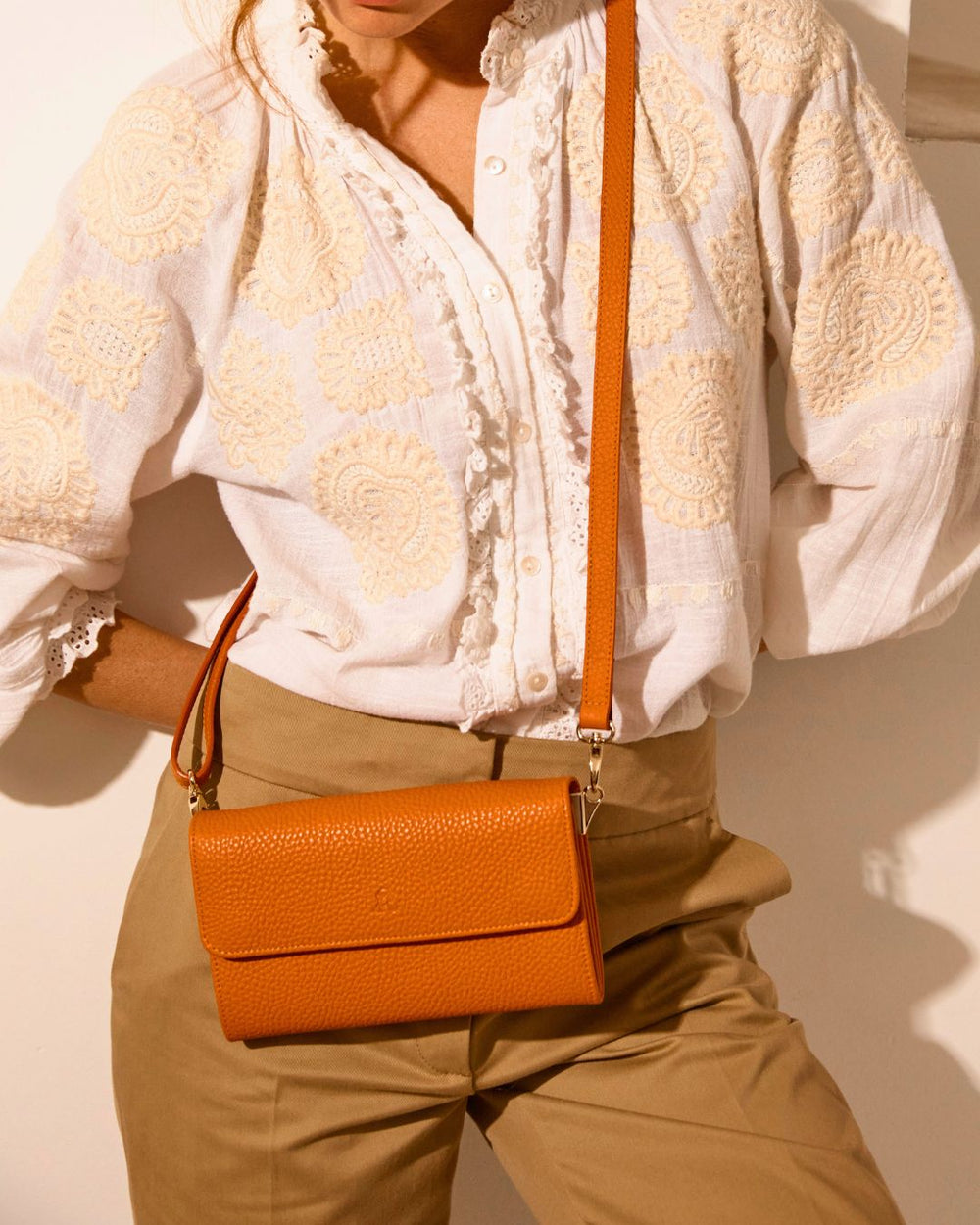 Notre pochette Raphaël en cuir façon vigogne orange vue portée par notre mannequin.