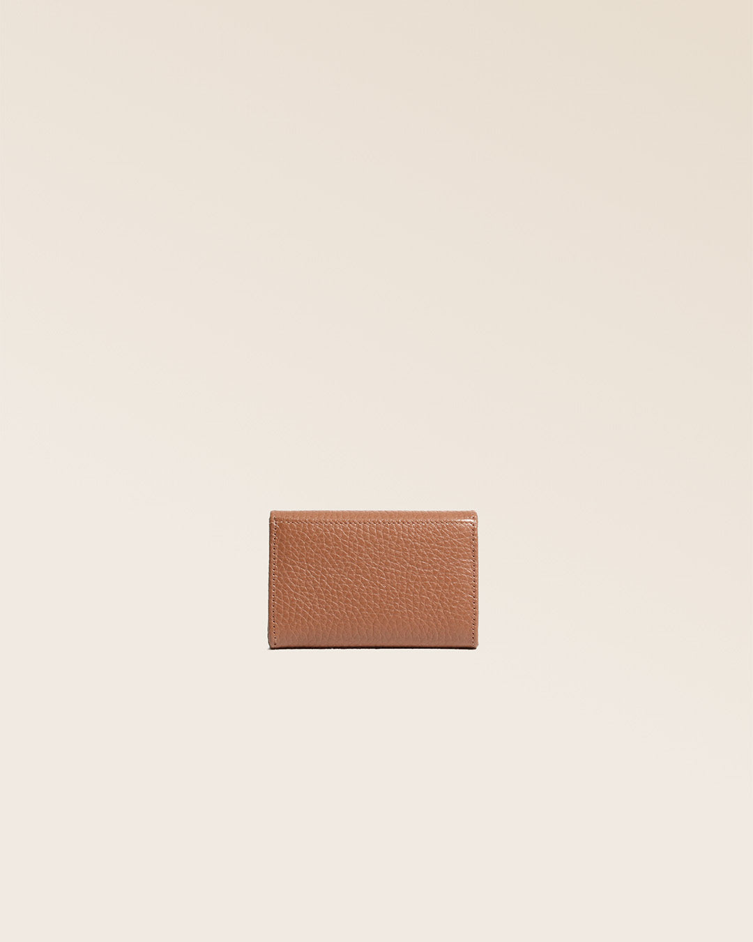 Notre porte-monnaie Alma en cuir façon vigogne fauve vu de dos en studio.